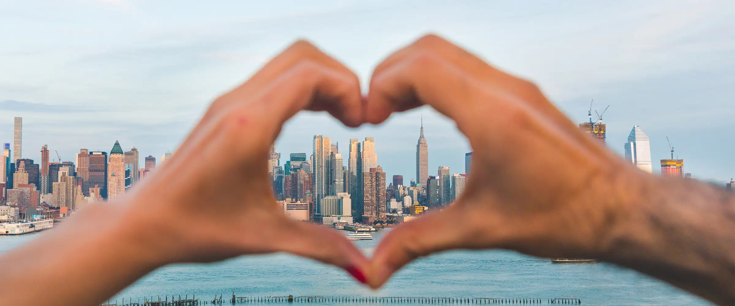 making hands in heart shape with NYC in the background